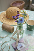Single stem vase with cut flowers and sunhat on table in Worth Matravers cottage Dorset England UK