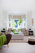 Neutral sunlit living room with green accent colours in Wandsworth home London England UK