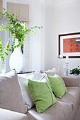 Leaf arrangement in large vase with sofa in bay window of Wandsworth home London England UK