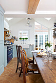 Wooden table and chairs in light blue fitted kitchen in Emsworth beach house Hampshire England UK