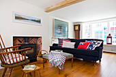 Dark blue sofa with exposed brick woodburning stove in living room of Emsworth beach house Hampshire England UK