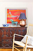 Chair at wooden sideboard with modern art and brass lamp in Emsworth home Hampshire England UK