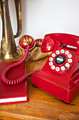 Bright red rotary dial telephone with notebook in Emsworth beach house Hampshire England UK