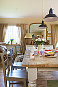 Gestrichene Stühle am Esstisch mit Pendelleuchten in einem Haus in Kent, England, Vereinigtes Königreich