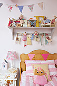Wooden headboard with bunting and soft toys in girls room in Kent family home England UK
