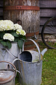 Metal watering can and barrel at wood clad exterior of Kent home England UK