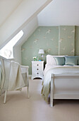 Vogelmustertapete mit weißem Bett und Stuhl im Schlafzimmer des Cottage in Dorset, Corfe Castle, England