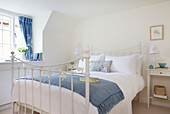 White wrought iron double bed with blue blanket in Dorset cottage Corfe Castle England UK
