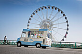 Man standing with bicycle on Brighton wheel promenade with ice cream van Brighton and Hove Sussex England UK