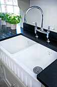 Double sink with chrome tap fitting and herbs in Woodchurch kitchen Kent England UK