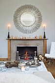 Circular mirror above lit fire in white living room of Faversham home Kent England UK