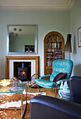 Turquoise armchair and wood burning stove in living room of Faversham home Kent England UK