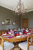 Christmas Crackers und Weingläser auf hölzernem Esstisch mit Kronleuchter in Faversham home Kent England UK