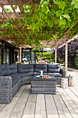 Graues Sofa auf Pergola mit Weinrebe im Garten von Rye, East Sussex, UK