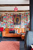 Orange leather sofa with patterned vintage wallpaper in Tenterden living room Kent UK