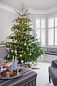 Christmas tree with glass baubles and striped ottoman in London home UK