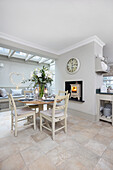 Winter lilies and lit woodburner in white open plan kitchen London UK