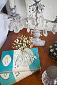 Cut flowers and paperback books with candlestick at bedside in 17th century Grade II listed East Sussex farmhouse UK