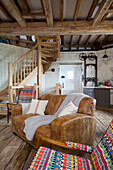 Tan leather sofa and wooden staircase in 'meal floor' of Grade ll listed windmill conversion Kent UK