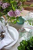 Cut flowers and glassware with plates on dining table in Grade ll listed windmill conversion Kent UK