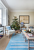 Sessel und Weihnachtsbaum mit blau-weiß gestreiftem Teppich im Pfarrhaus von Warehorne, Kent, Großbritannien