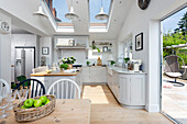 Hellgraue offene Wohnküche mit drei Oberlichtern und Pendelleuchten und Doppelflügeltüren zum Garten Oxfordshire UK