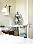 Oriental urn in side table with lamp in bedroom of Kensington home London England UK