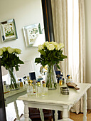 Cut roses on dressing table with perfume bottles in Kensington home London England UK
