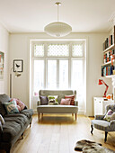 Sofas with cushions and sunlit French doors in living room of London home England UK