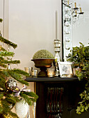 Christmas tree with silverware on black fireplace in London home England UK