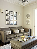 Lit candle on silver ottoman in living room with grey sofa and artwork display in classic London home England UK
