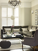 Grey corner sofa with square shaped coffee table and wicker stool in London home England UK