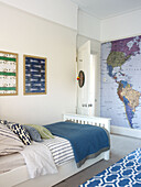 Blue blanket on single bed in boys room with large wall map in London home England UK