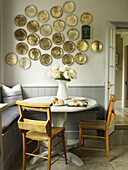 Wall-mounted plate display above table with pew chairs in East Sussex country house England UK