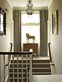 Horse statue on chest of drawers at sunlit staircase window of East Sussex country house England UK