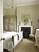Mirror above fireplace with wardrobe and coir matting in bedroom of East Sussex country house England UK
