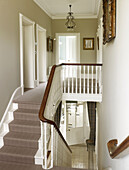 Polierter Holzhandlauf im mit Teppich ausgelegten Treppenhaus eines klassischen Landhauses in East Sussex, England, UK