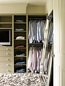 Shirts and blouses in bedroom storage unit with full length mirror in North London townhouse England UK