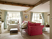 Rosafarbenes Sofa mit Sessel und Fußbank am Fenster eines Wohnzimmers in Nottinghamshire England UK