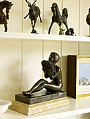 Seated figurine with animal statues on living room shelf in Nottinghamshire home England UK