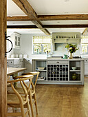 Wooden barstools in timber-framed kitchen with wine storage in West Sussex farmhouse kitchen, England, UK