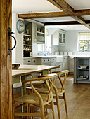 Wooden chairs at table with dresser in timber-framed West Sussex farmhouse kitchen, England, UK