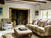 Checked sofa with ottoman at fireside in West Sussex farmhouse, England, UK