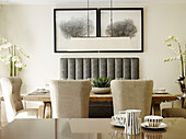 Upholstered chairs with framed artwork above dining table in London townhouse, UK