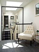 Buttoned armchair in mirrored staircase landing of London townhouse, UK