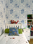Dragon on headboard of single bed with palm tree wallpaper in boy's room, London townhouse, UK