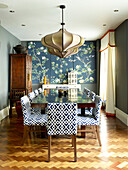 Oriental panels in dining room with upholstered chairs in London townhouse apartment, UK