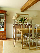 Dining room with ceiling beam above table and sideboard in Oxfordshire cottage, England, UK