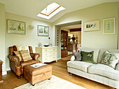 Brown leather armchair and footstool with sofa in modernised Oxfordshire cottage, England, UK