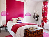 Wooden chest at foot of girls' bed with glass pendant shades and painted panel, London home, UK